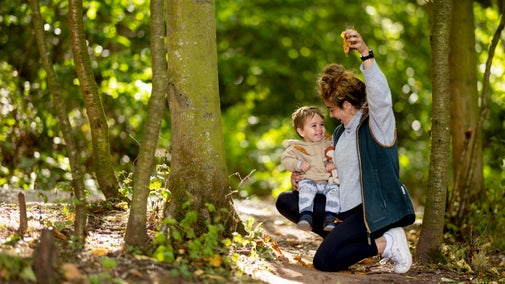 Image shows a child and mum playing with autumn leaves